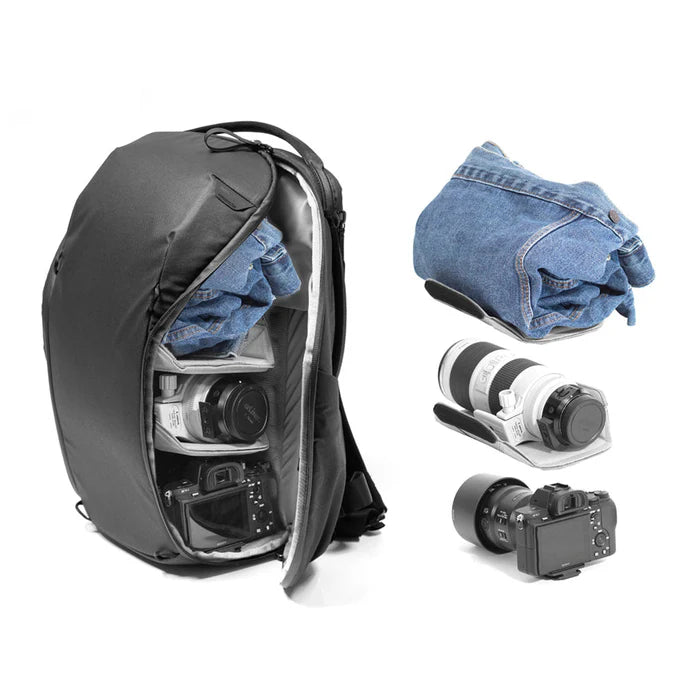 Black backpack with camera equipment and denim items on a white background