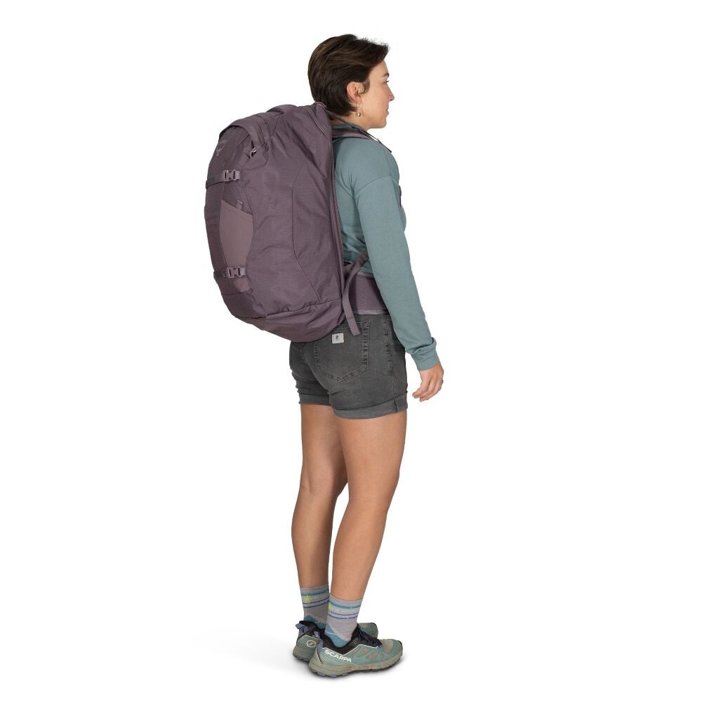Woman wearing a large purple backpack on a white background