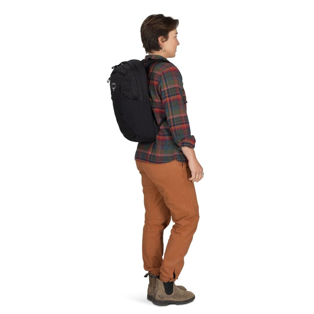 Person wearing a black backpack, plaid shirt, and brown pants on a white background