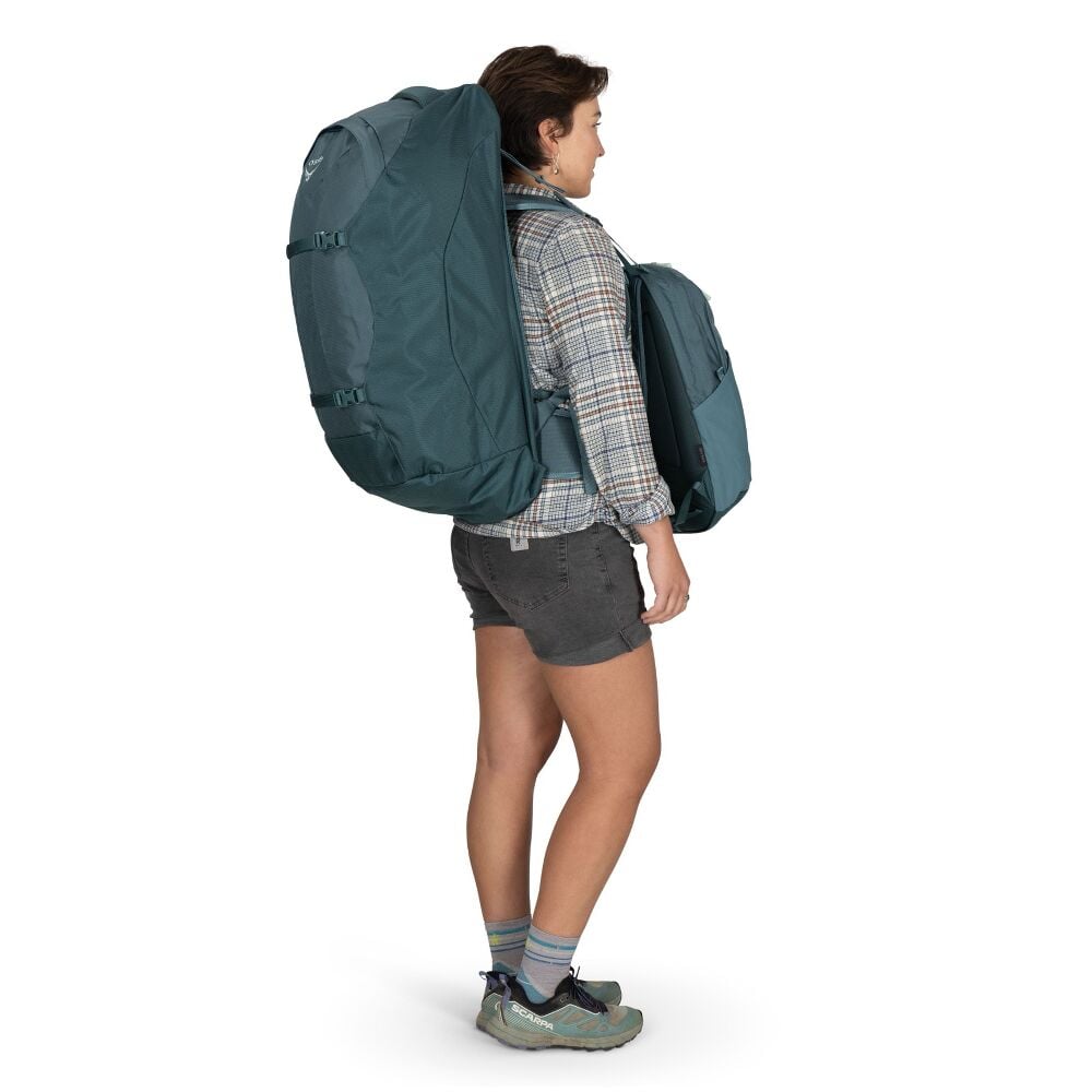 Person wearing a large teal backpack with matching front pack on a white background