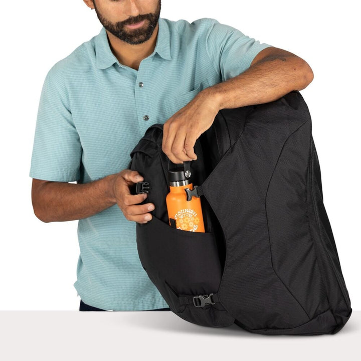 Man opening a black backpack with an orange water bottle in the side pocket