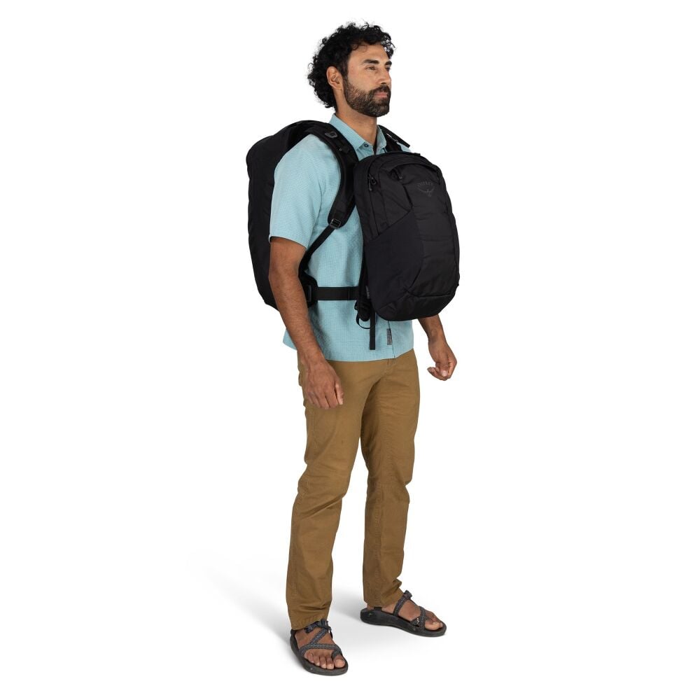 Man wearing a black backpack and matching front pack on a white background