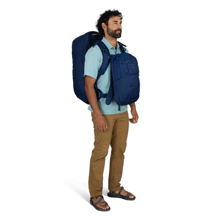 Man wearing a blue backpack and matching front pack on a white background