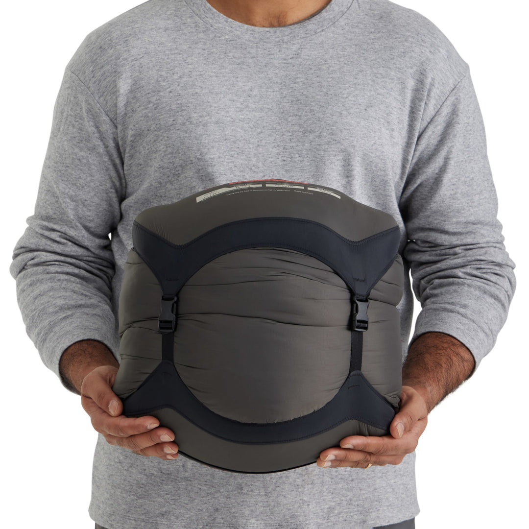 Person holding a sleeping bag in a grey compression sack