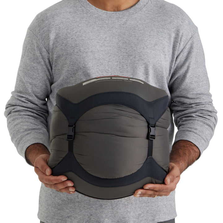 Person holding a sleeping bag in a grey compression sack