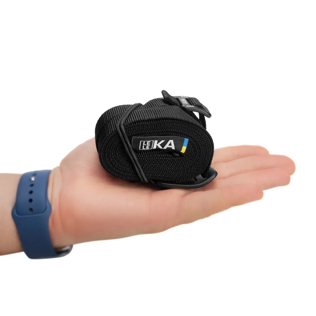 Black rolled up hammock strap with Leleka branding resting on a person&