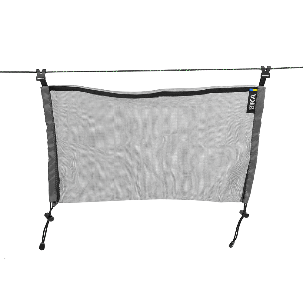 Gray mesh hammock with black straps hanging on a wire against a white background