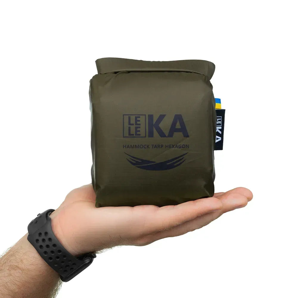 Hand holding a green LELEKA hammock tarp hexagon on a white background