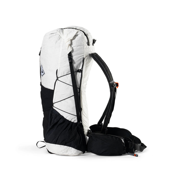 A technical hiking backpack shown from a three-quarters rear angle on a clean white background. The backpack features a white upper shell, a black lower body panel, black shoulder straps, and a black hip belt with a small orange adjustment slider.