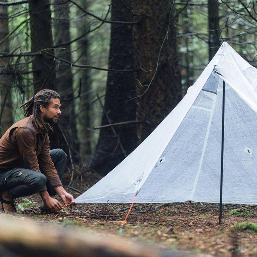 Person setting up a tent in a forest