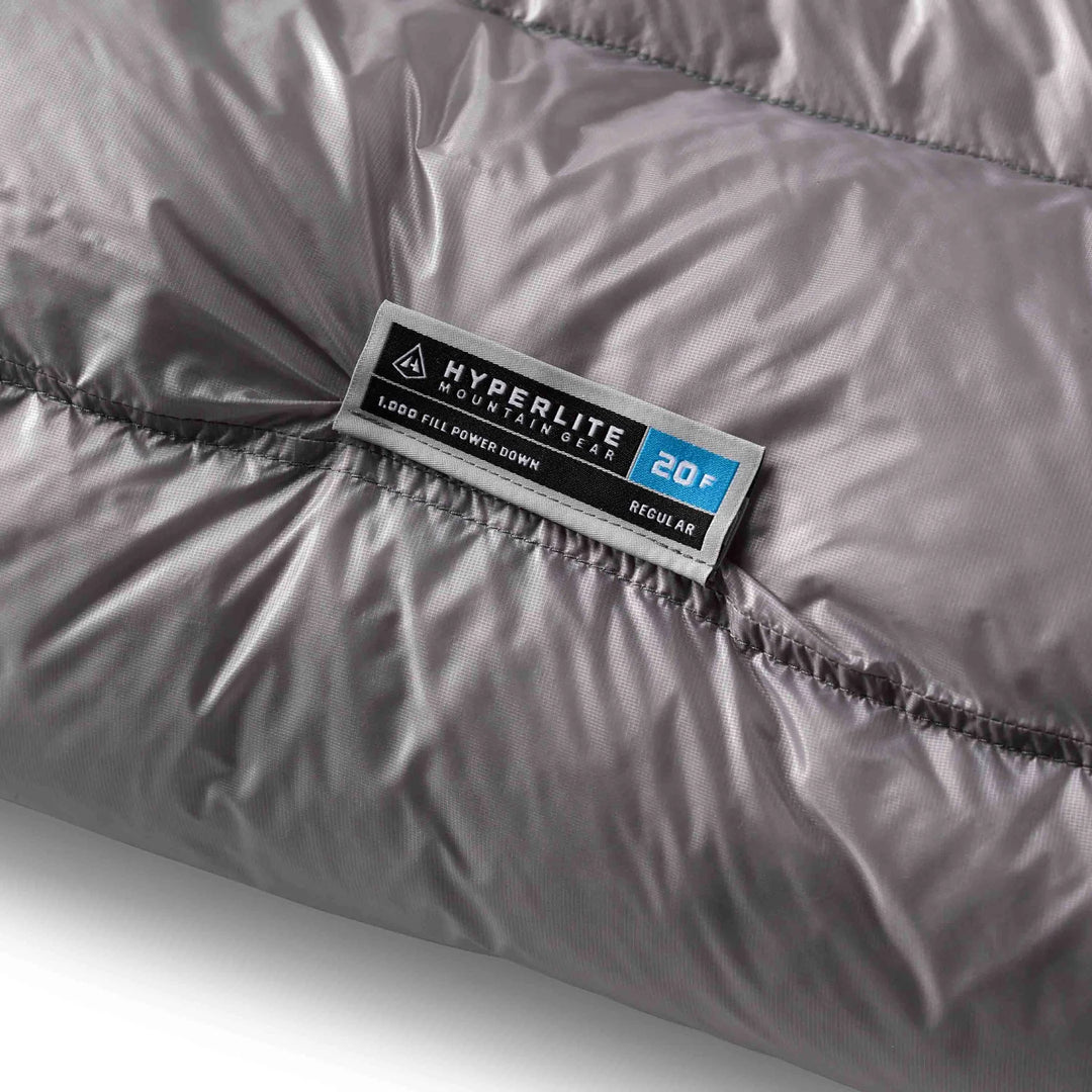 Close-up of a Hyperlite Mountain Gear sleeping bag label on gray fabric.
