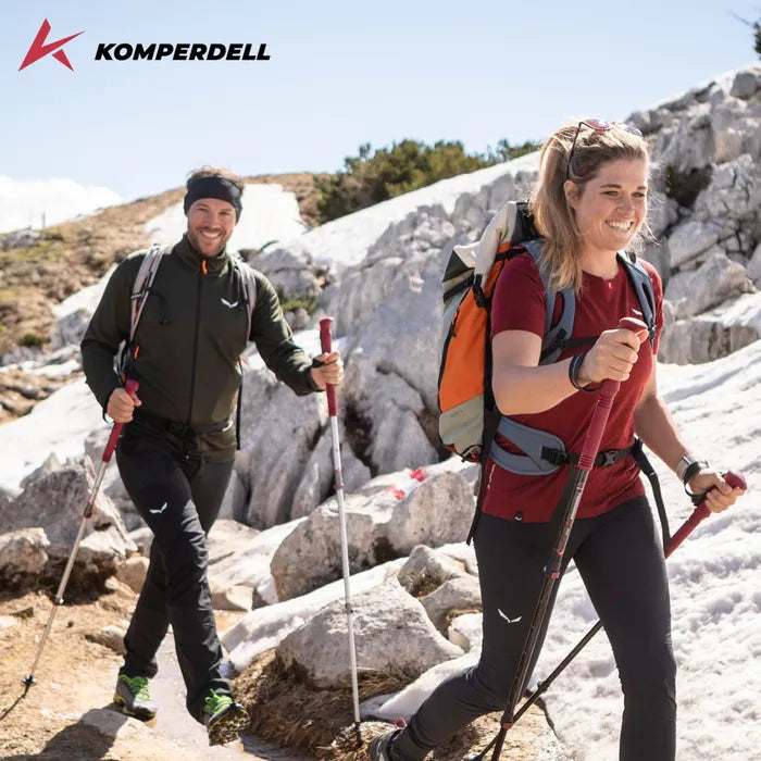Two hikers with backpacks and trekking poles on a rocky trail. Komperdell Logo in corner