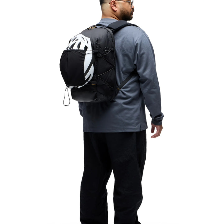 Person wearing a black backpack with a helmet attached on a white background