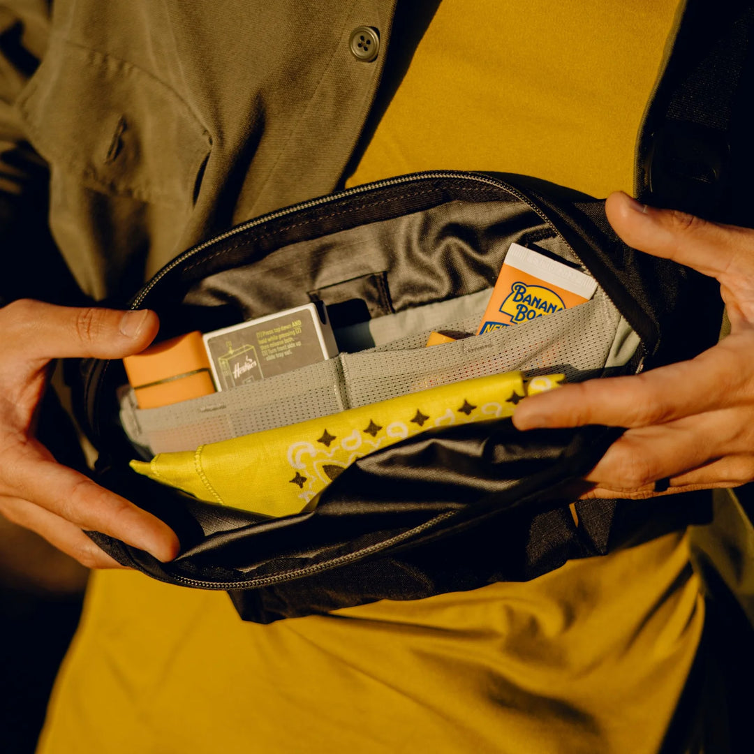 Person opening a black pouch to reveal items including a yellow banana-shaped object and a card.