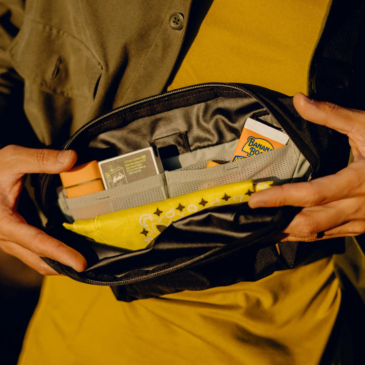 Person opening a black pouch to reveal items including a yellow banana-shaped object and a card.