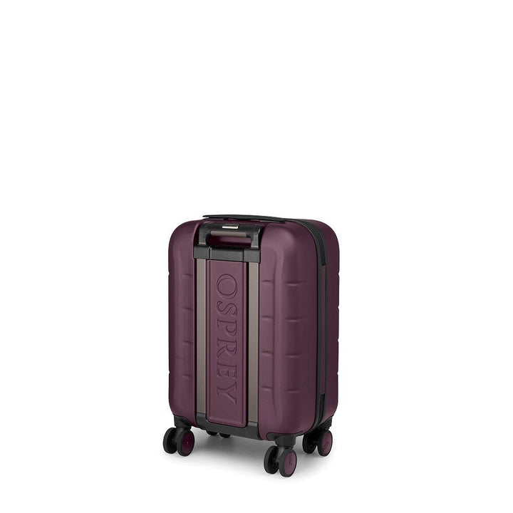 A hard-shell spinner suitcase in a deep plum purple color with a vertical Osprey logo plaque on the front, set against a plain white background.