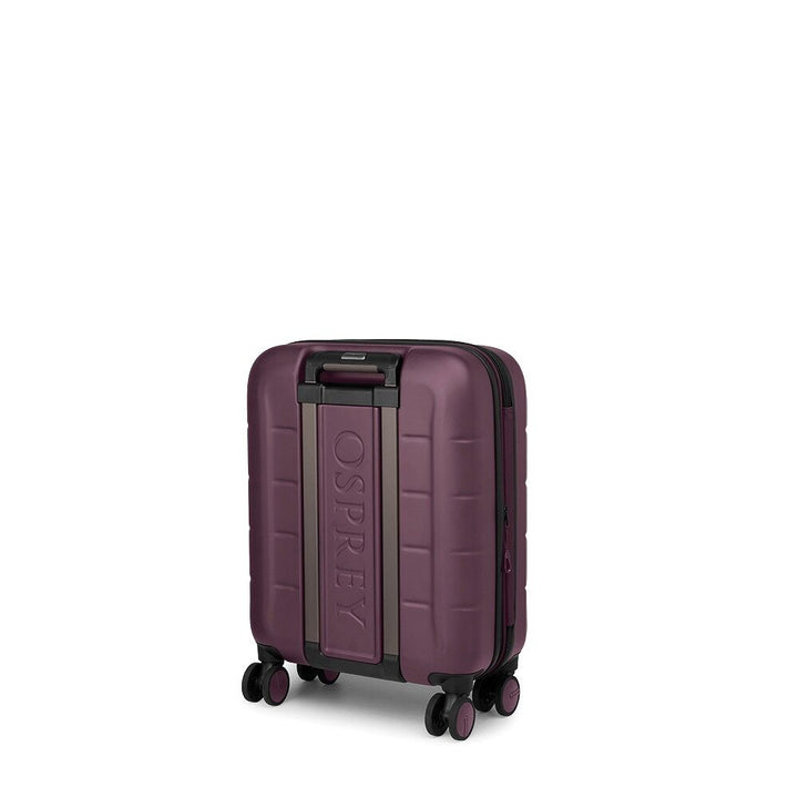 A hard-shell carry-on suitcase in a deep plum purple color, featuring a vertical metallic bronze accent panel with the embossed brand name &
