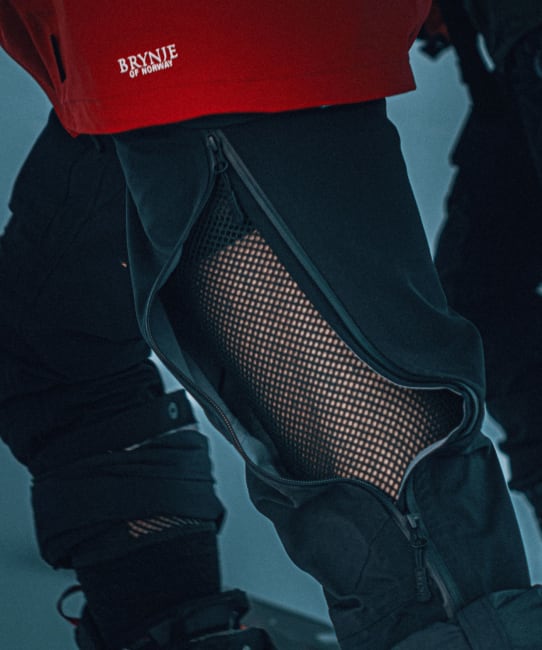 Close-up of black hiking gear with mesh baselayer, worn by a person in a red jacket with &