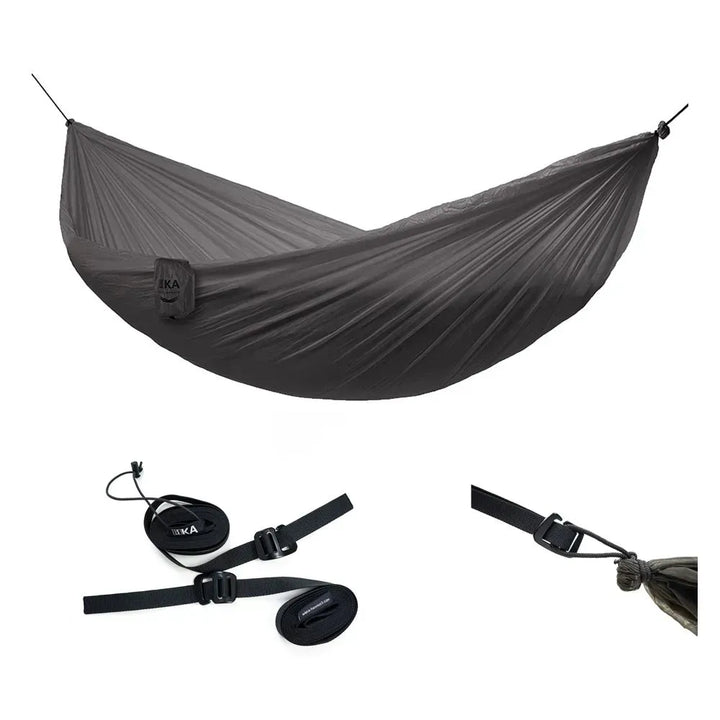 A dark gray lightweight camping hammock suspended between two black ropes, shown with its included black straps and buckles on a plain white background.