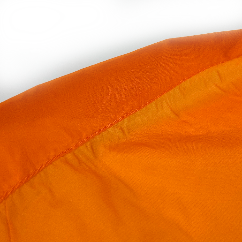 Close-up of an orange ripstop fabric item, showing the texture and stitching detail against a white background.