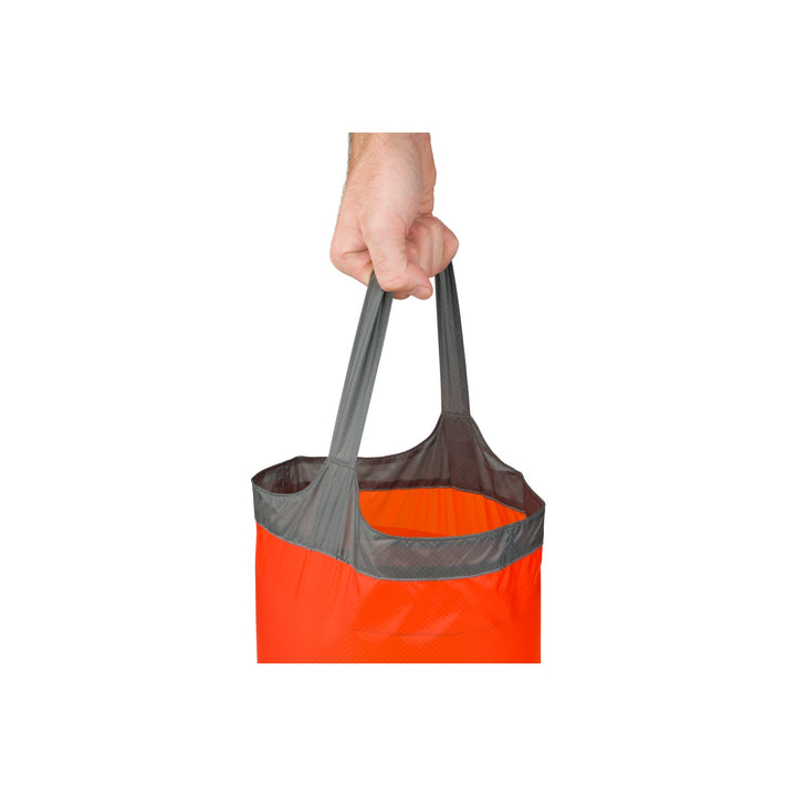 Orange folding bucket full of water and held by a hand