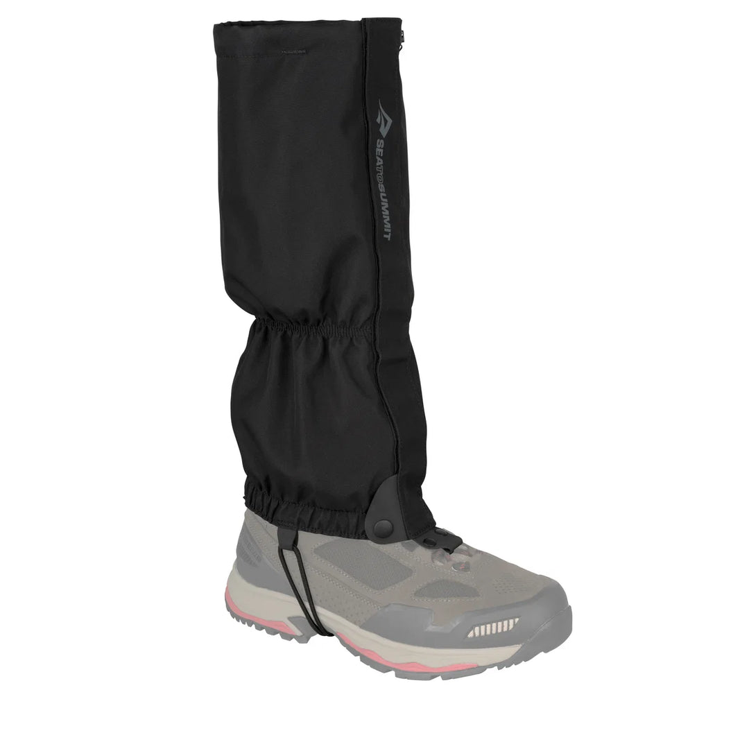 Black gaiter over a hiking boot on a white background