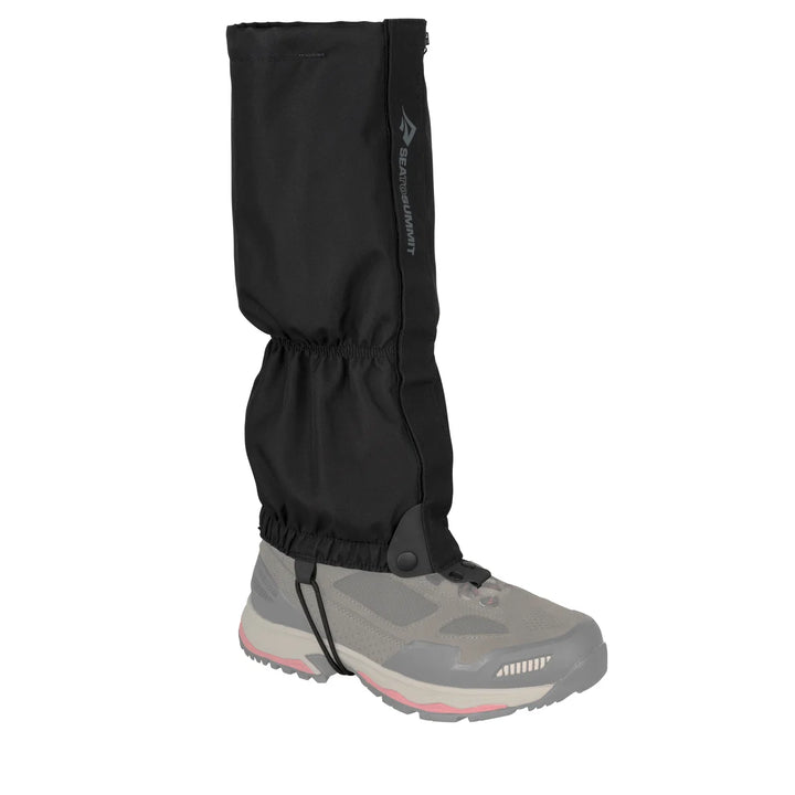 Black gaiter over a hiking boot on a white background