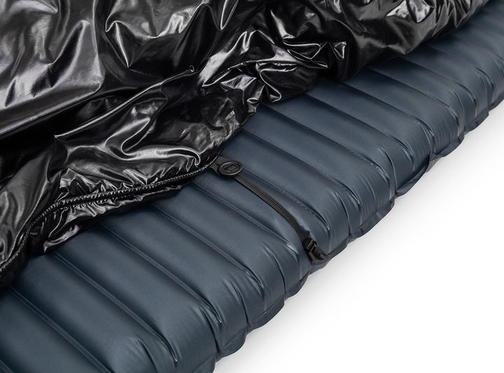Inflatable sleeping pad with black quilt on top on a white background