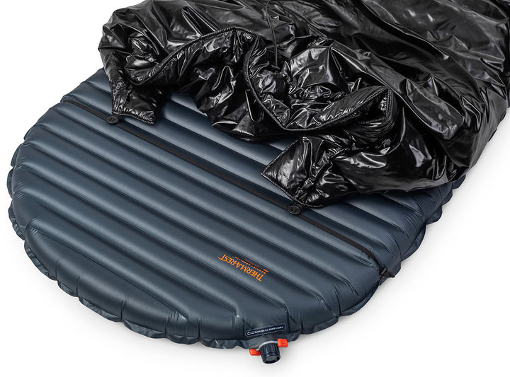 Inflatable sleeping pad with black quilt on top on a white background
