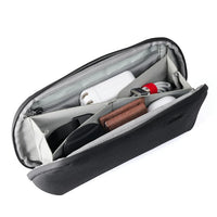 Inside of dark grey accessory pouch with light grey interior and different pockets for organization on a white background