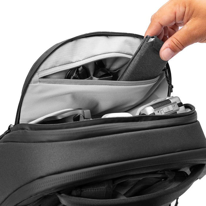 Person opening a black backpack with a hand reaching inside