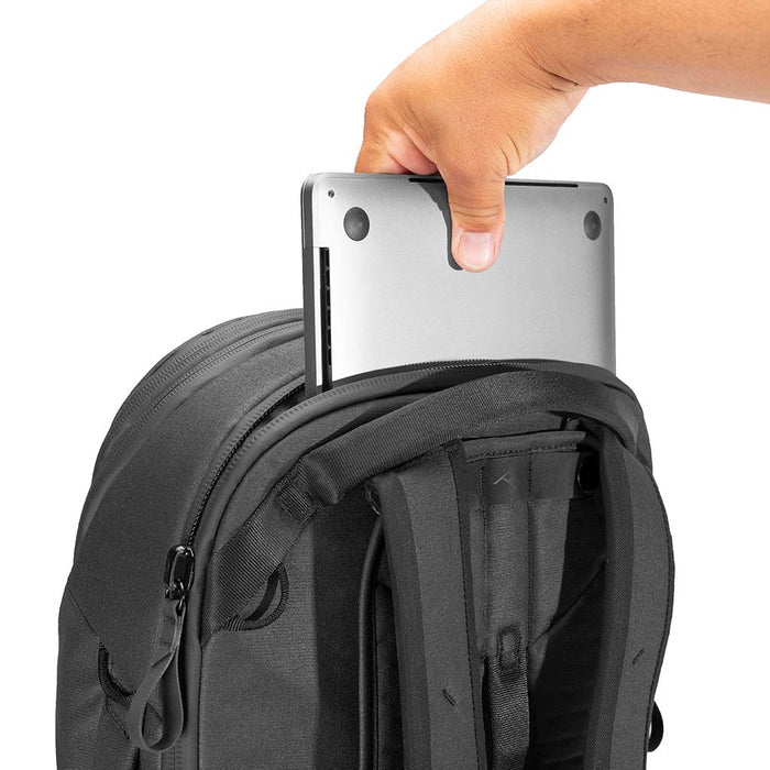 Person holding a tablet above a black backpack on a white background