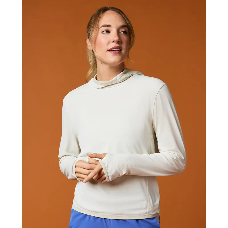 Woman wearing a white long-sleeve shirt with a hood against an orange background