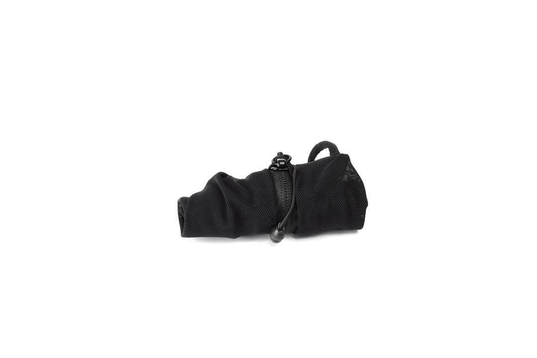 A rolled up black mesh packing cube on a white background 
