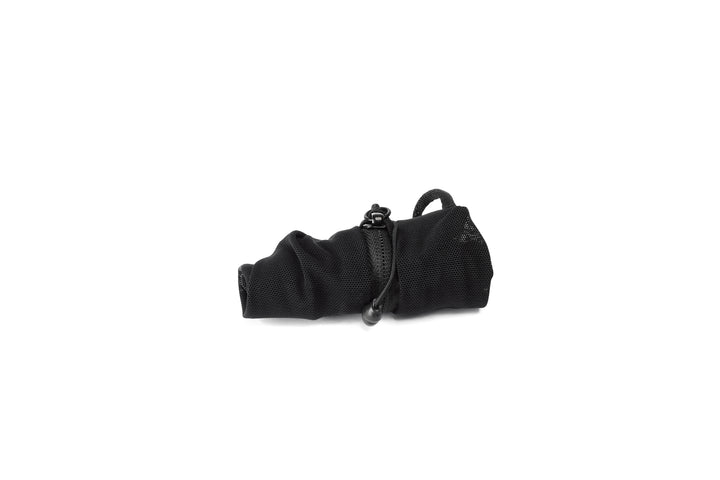 A rolled up black mesh packing cube on a white background 