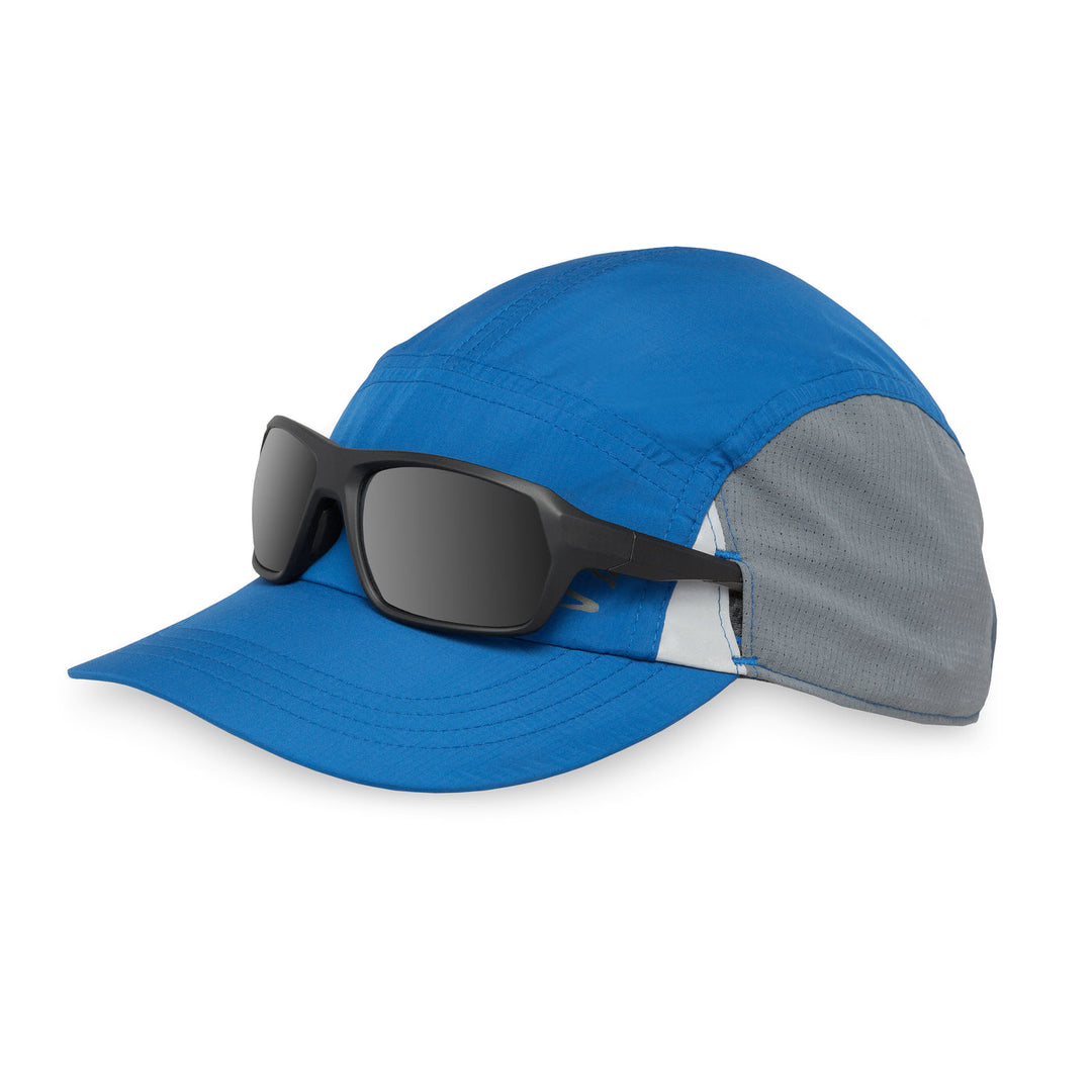Blue cap with grey visor and black sunglasses on a white background