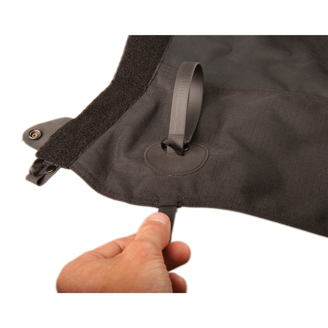 Person attaching a strap to a black gaiter