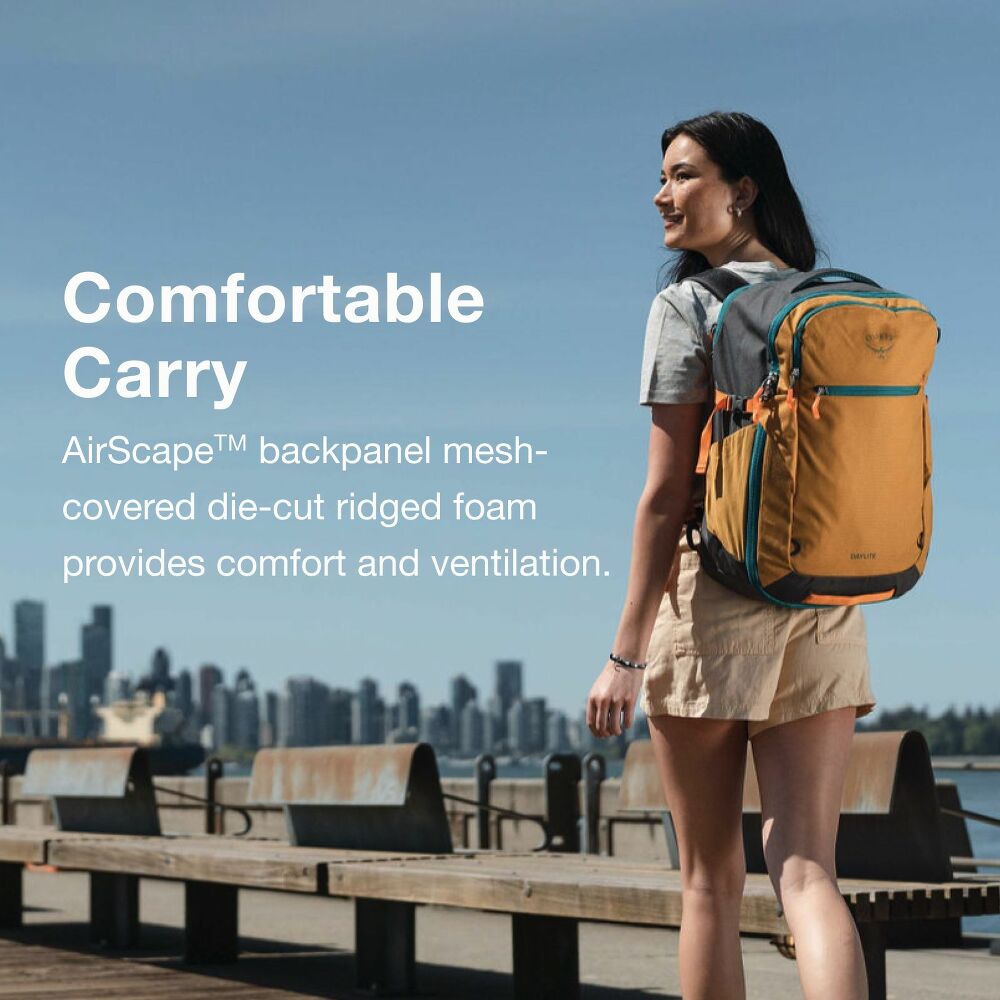 Woman with a yellow backpack standing on a boardwalk with a city skyline in the background