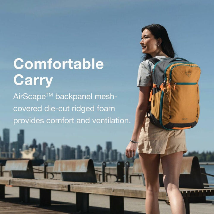 Woman with a yellow backpack standing on a boardwalk with a city skyline in the background