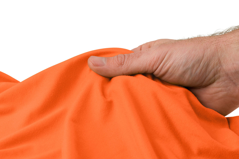 Person feeling the fabric of an orange travel towel