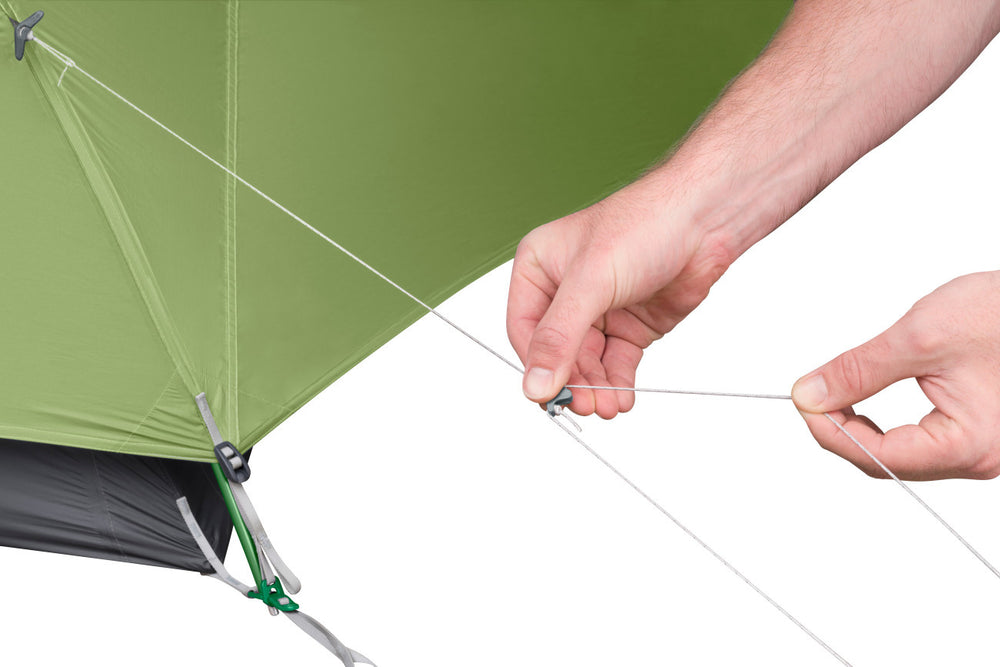 A person demonstrating the tightening of tent's guyline